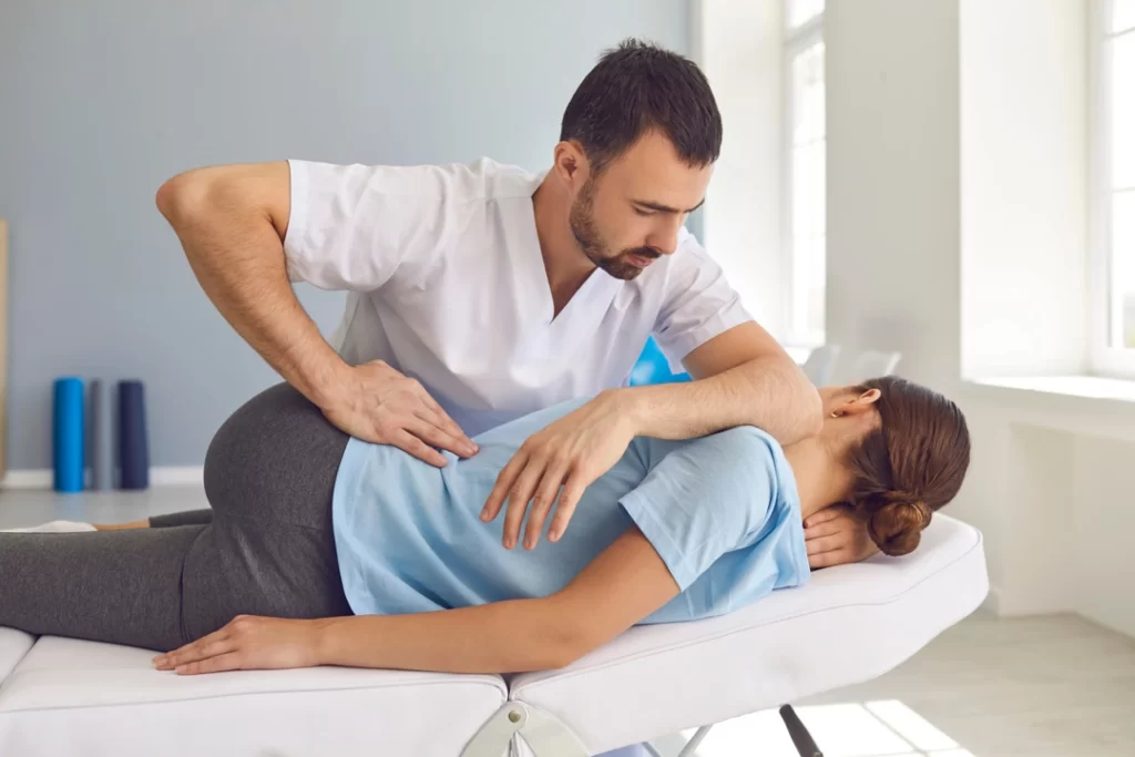 Doctor chiropractor or osteopath fixing lying woman back in manual therapy clinic