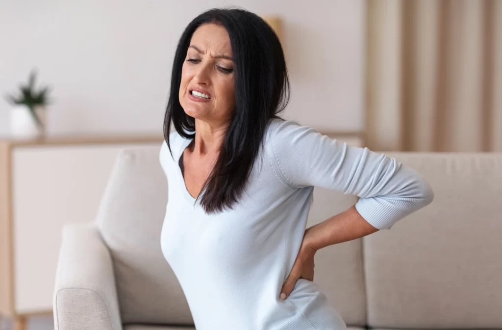 Mature woman having Vertebrogenic low back pain while sitting on the couch.