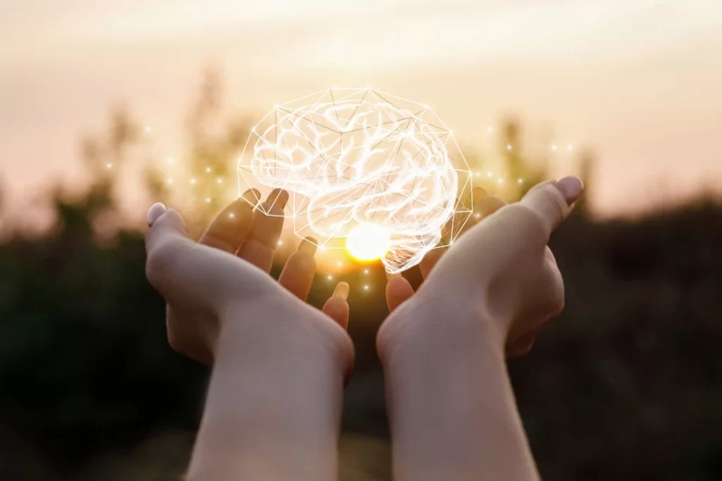 beaming brain in girl's hand with sunset background