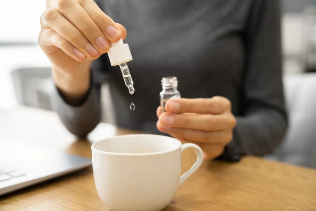 girl dropping out CBD oil in her coffee