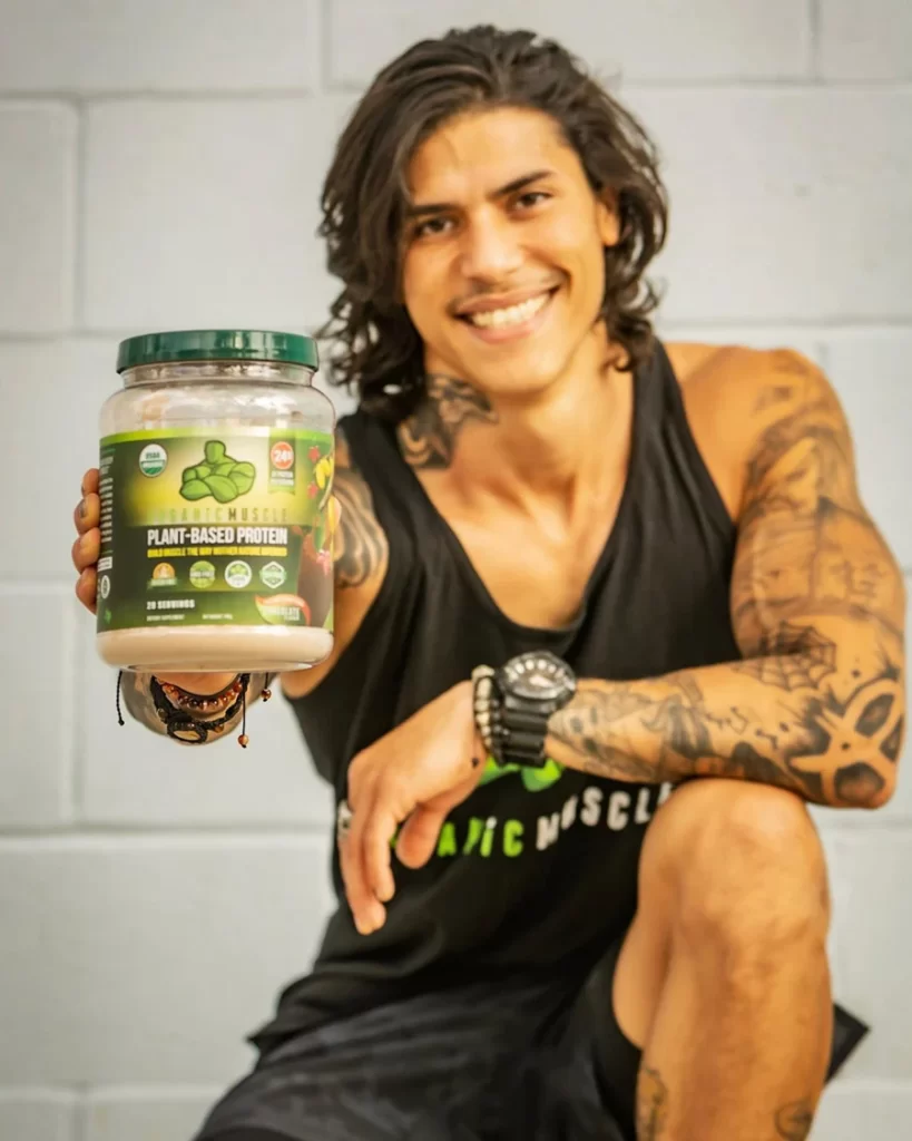 Athlete holding organic Muscle plant-based protein bottle.