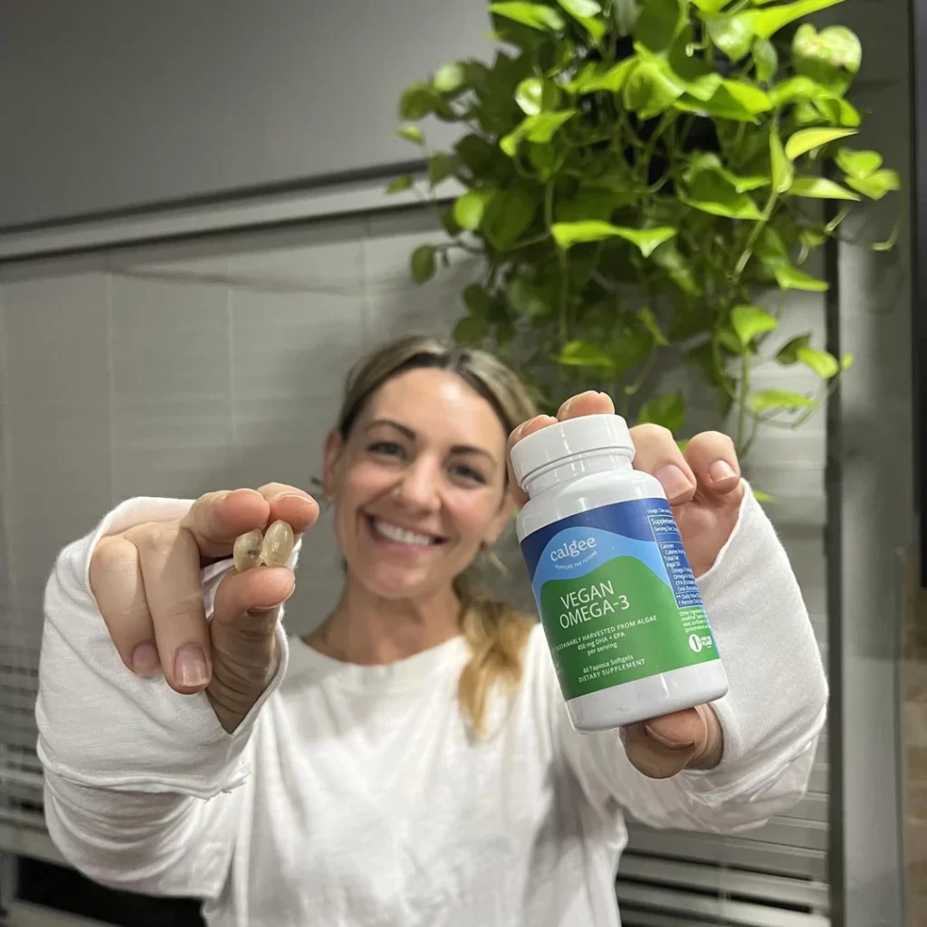 woman holding calgee vegan omega 3 capsules and bottle in each hand.