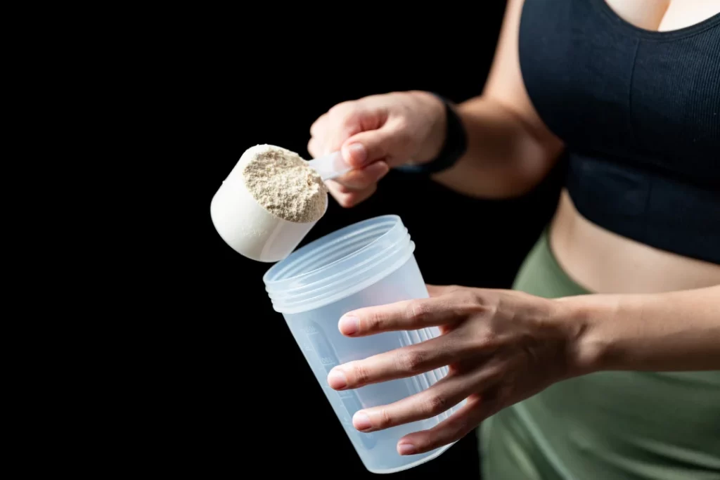 Sport girl pouring protein in a jar before a workout. 
