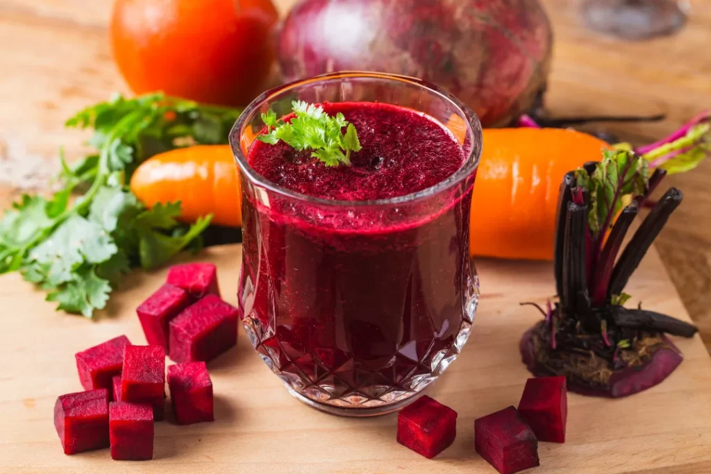 red beetroot juice with carrot and beetroot behind the glass.