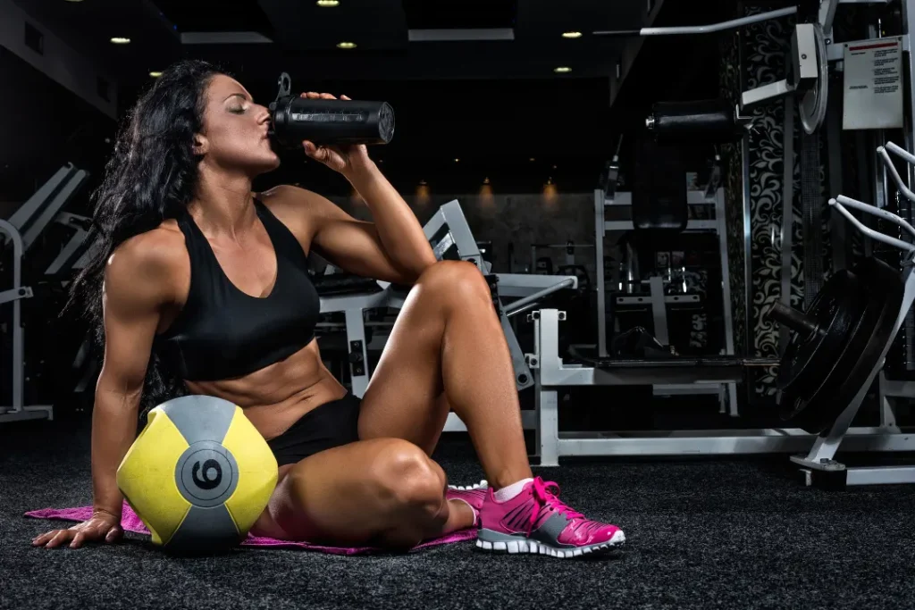 Women drinking protein drinks in the gym. 