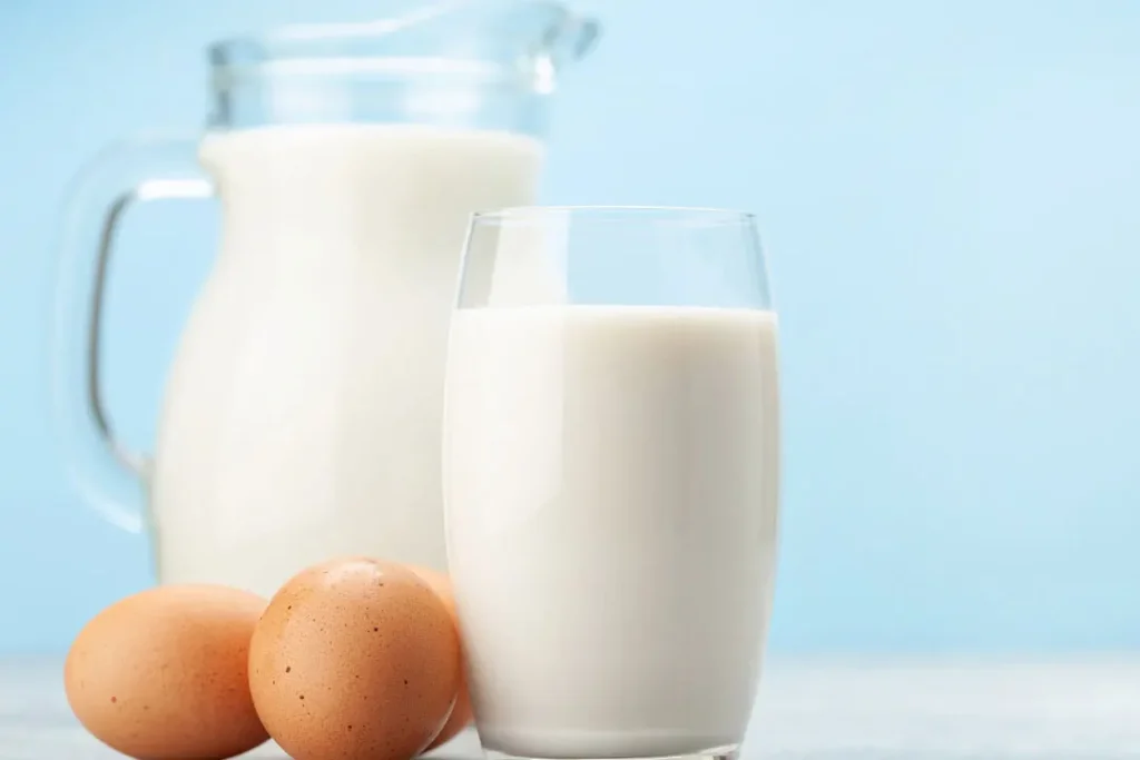 milk in glass and jug and egg in blue background